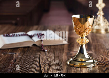 Die erste heilige Kommunion. Das Kreuz, Bibel, Rosenkranz und goldenen Kelch auf braunem Hintergrund. Stockfoto