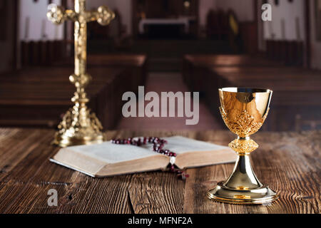 Die erste heilige Kommunion. Das Kreuz, Bibel, Rosenkranz und goldenen Kelch auf braunem Hintergrund. Stockfoto