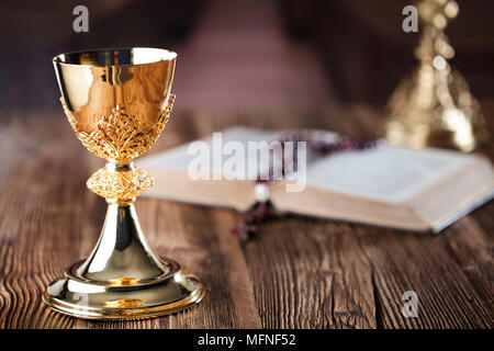 Die erste heilige Kommunion. Das Kreuz, Bibel, Rosenkranz und goldenen Kelch auf braunem Hintergrund. Stockfoto