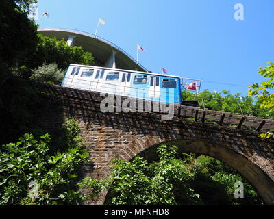 Touristischer Zug auf Standseilbahn auf steinigen Brücke in europäischen Stadt Locarno in der Schweiz über dem Lago Maggiore im Kanton Tessin mit klaren blauen Himmel Stockfoto