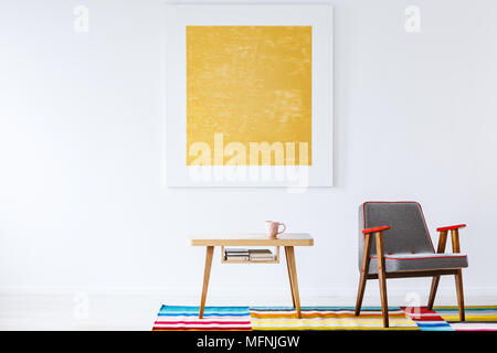 Bunte spot mit Holzmöbeln in einem eleganten, weißen Wohnzimmer Einrichtung mit moderner Kunst auf eine leere weiße Wand entspannen Stockfoto