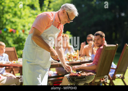 Ältere Menschen kochen Fleisch am Grill im Freien Stockfoto