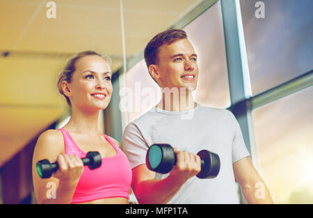 lächelnde junge Frau mit personal Trainer im Fitness-Studio Stockfoto