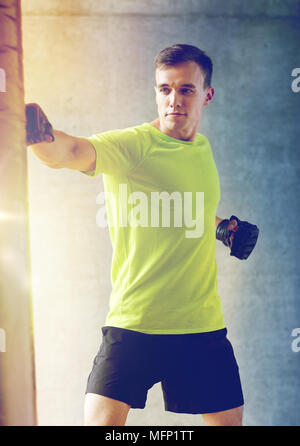 junger Mann in Boxen mit Boxsack Handschuhe Stockfoto