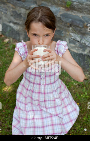 Sieben Jahre alten Mädchen ist das Trinken der Milch im Sommer draußen Stockfoto