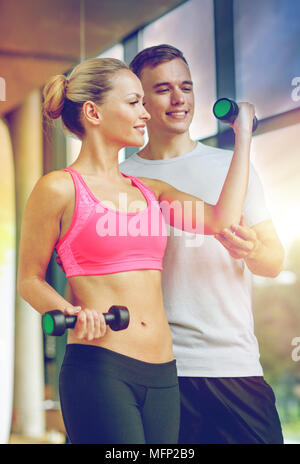 lächelnde junge Frau mit personal Trainer im Fitness-Studio Stockfoto