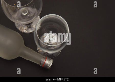 Glas Flasche liegend mit zwei leeren Gläsern dunklen Hintergrund Alkoholismus Konzept Alkoholsucht Stockfoto