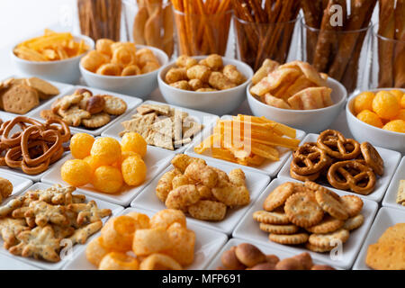 Zeilen von vielen Arten von herzhaften Snacks aus weisser Keramik Geschirr. Stockfoto