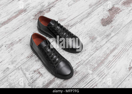 Schwarze Leder Turnschuhe auf hellem Laminat. Stockfoto
