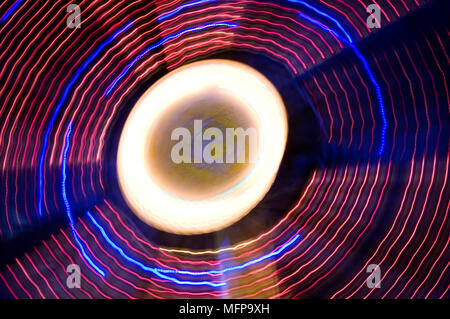 Eine energetische Abstract der Lichter von einem Jahrmarkt Riesenrad bei Nacht zeigen die spinning Ringe an einer langen Belichtungszeit. Stockfoto