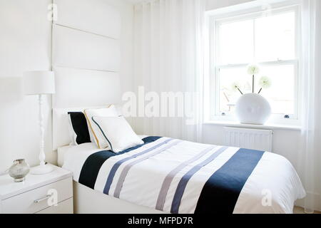 Doppelbett in modernes Schlafzimmer mit blau gestreiften Bettdecken Stockfoto