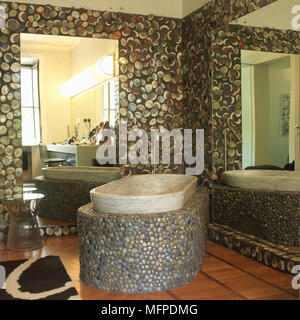 Eine abstrakte Kiesstrand Effekt Bad mit einem Spiegel und Marmor Badewanne in Kies und Stein auf Holz Bodenbeläge mit abstrakten Bodenmatte Stockfoto