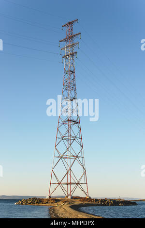 Pylon und Transmission Power Line an der Küste vor Himmel. Stockfoto