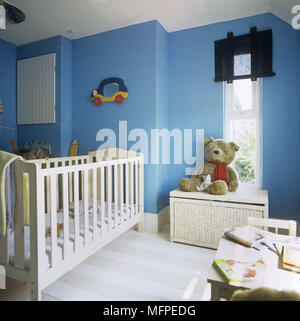 Details zu Kinderbett und Teddy sitzt auf der Brust durch ein Fenster in einem traditionellen Baby? Schlafzimmer Stockfoto