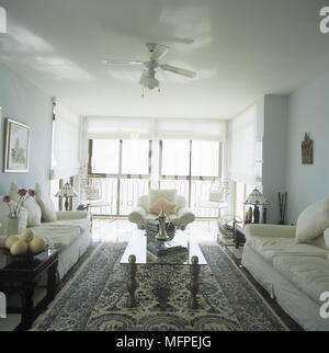 Wohnzimmer mit Sofas und einem Sessel, die um einen Couchtisch aus Glas Stockfoto