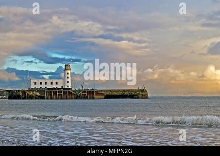 Scarborough Leuchtturm in der Dämmerung, stehend unter Nordsee Wolken hell durch die sterbende Strahlen der Wintersonne. Stockfoto