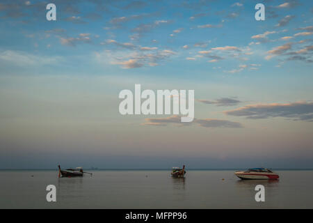 Boote auf ruhigem Wasser bei Sonnenaufgang in Thailand Stockfoto