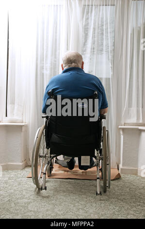Behinderte ältere Mann saß in seinem Rollstuhl aus dem Fenster Model Release suchen Stockfoto