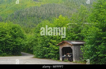 Ketchikan, Alaska, USA: eine staubbedeckte Antique Car in einem Holzhaus im Wald auf einer Landstraße im amerikanischen Nordwesten Schuppen. Stockfoto