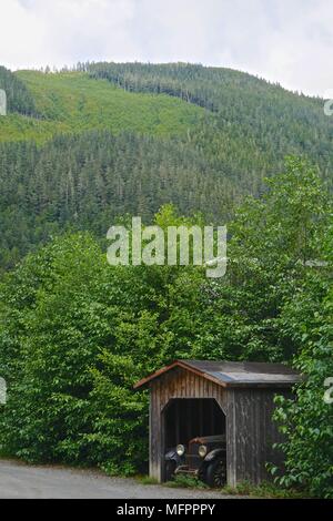 Ketchikan, Alaska, USA: eine staubbedeckte Antique Car in einem Holzhaus im Wald auf einer Landstraße im amerikanischen Nordwesten Schuppen. Stockfoto