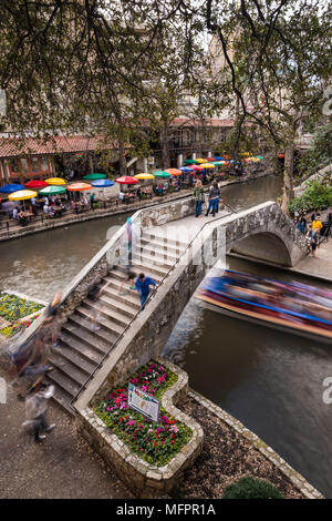 Teil der San Antonio Riverwalk mit Menschen zu Fuß über eine Brücke über den Fluss und die Gebäude und Restaurants in Spring, Texas, USA Stockfoto