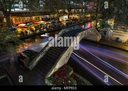 Teil der San Antonio Riverwalk mit Menschen zu Fuß über eine Brücke über den Fluss und die Gebäude und Restaurants in Spring, Texas, USA Stockfoto