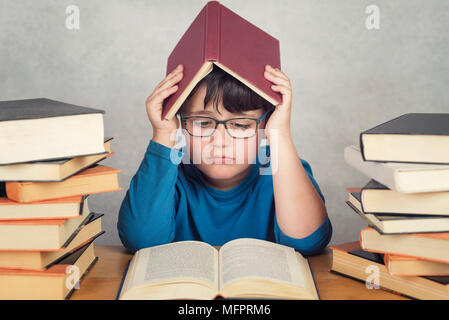 Traurige und nachdenkliche Junge mit Bücher auf einem Tisch Stockfoto