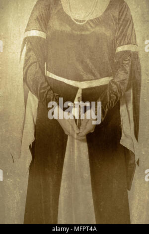 eine Frau im viktorianischen Kleid ein Kruzifix in ihren Händen hält Stockfoto