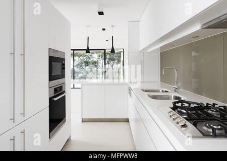 Moderne Küche mit weißer Arbeitsplatte, Spüle und große Fenster