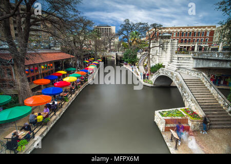 Teil der San Antonio Riverwalk mit Menschen zu Fuß über eine Brücke über den Fluss und die Gebäude und Restaurants in Spring, Texas, USA Stockfoto