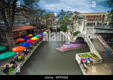 Teil der San Antonio Riverwalk mit Menschen zu Fuß über eine Brücke über den Fluss und die Gebäude und Restaurants in Spring, Texas, USA Stockfoto