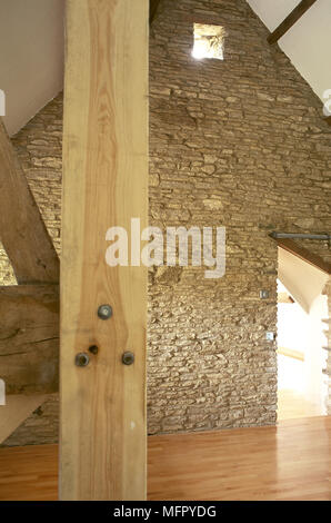 Umgebaute Scheune mit Holzfußboden und freiliegenden Dachstühle, Wände aus Stein, und eine kleine, quadratische Fenster und Tür. Stockfoto