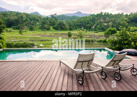 Resort Swimmingpool und Liegestühlen mit Blick auf die Berge Stockfoto