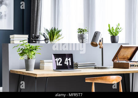 Seite Winkel einer hölzernen Schreibtisch mit einem Laptop angezeigt, Anlage, Lampe, Bücher und Schallplatten stehen am Fenster Stockfoto