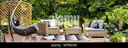 Das Essen bei einem Picknick und kalte Limonade in Glas Karaffe auf einem Tisch stehend auf einer Terrasse mit Hängematte Stuhl gelegt Stockfoto