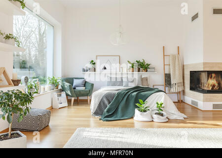 Helles Schlafzimmer mit King-Size-Bett, Teppich, Sessel, Kamin, Fenster und Leiter Stockfoto