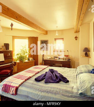 Land Schlafzimmer in Round House neutrale Wände Balkendecke Pendelleuchten gestreifte Bettdecken Kissen Kleidung gefaltet gemusterte Decke Seite Einheiten ope Stockfoto