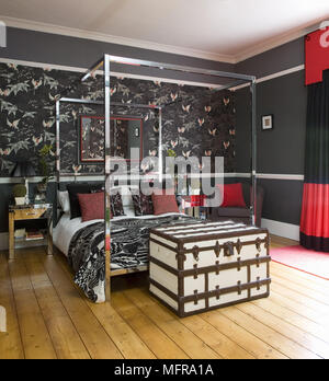 Altmodische trunk am Fuß aus Metall Himmelbett in dramatischen Schwarz und Rot Schlafzimmer Stockfoto