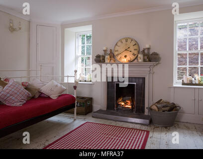 Stil der Zeit Schmiedeeisen Sofa mit roten Sitz neben dem Kamin mit brennenden Feuer Stockfoto