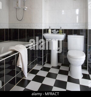 White Suite von Sockel Waschbecken zwischen Badewanne und WC in Schwarz und Weiß gehaltenes Badezimmer Stockfoto