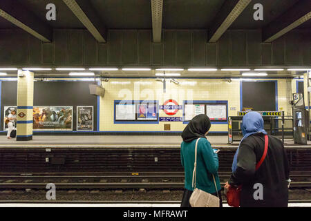 London, Großbritannien - 04 Mai, 2018 - Zwei muslimische Frauen warten auf der Plattform in der Aldgate East U-Bahn-Haltestelle Stockfoto