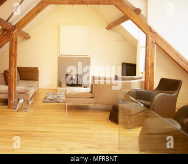 Wohnzimmer mit Holzfußboden, warf die Decke mit Holzbalken und einen Sitzbereich mit einem hellen Feuer im Kamin. Stockfoto