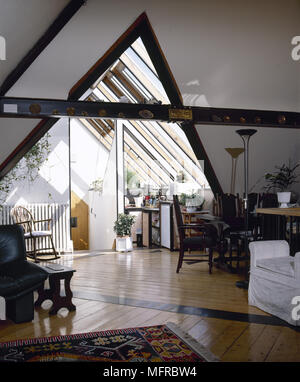 Wohn- und Essbereich mit Holzboden, Satteldach mit Holzbalken und Oberlichtern. Stockfoto