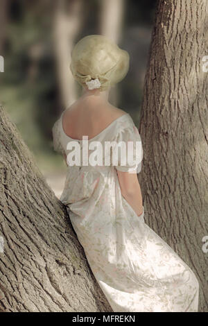 eine Frau in einem geblümten Kleid sitzt auf einem Stamm Stockfoto