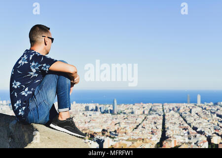 Nahaufnahme eines jungen kaukasischen Mann, von hinten gesehen, oben auf einem Hügel Beobachten der Stadt Barcelona, Spanien, unter ihm Stockfoto