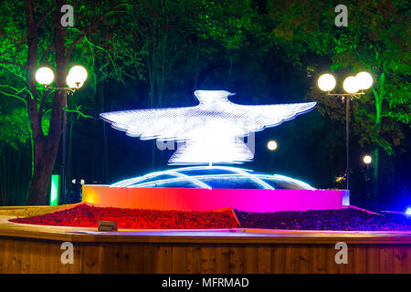 Sochi, Russland - November 17, 2017: Nacht Landschaft, die mit der drehenden beleuchtete Skulptur einer Taube auf dem festivalny Square Stockfoto