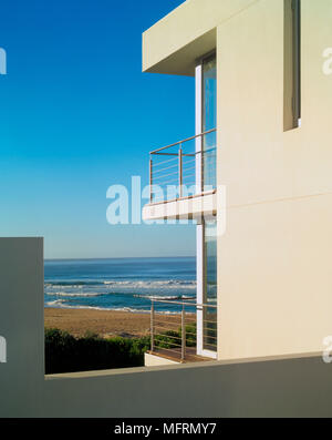 Ein Detail eines von außen ein modernes, weiß getünchtes Haus mit offenen Balkon mit Geländer aus Stahl mit Blick auf den Ozean Stockfoto