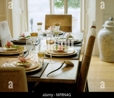 Ein Detail einer modernen neutralen Esstisch und Stühlen Platz Einstellungen für Abendessen Geschirr Gläser gelegt Stockfoto