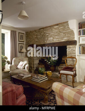 Landhaus Wohnzimmer mit einem hölzernen Couchtisch und Sesseln vor einem Stein Kaminecke. Stockfoto