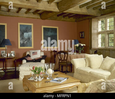 Land Wohnzimmer mit Holzbalkendecke, komfortabler Sitzbereich, gerahmte Kunstwerke und einen geschlossenen Fensters. Stockfoto